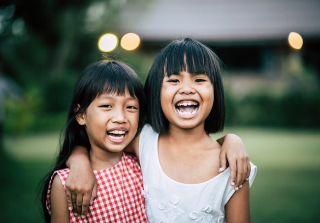 Two little girls friends playing funny in the park
